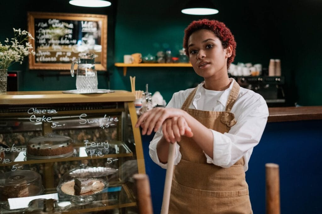 Young barista standing confidently in a warm and inviting café environment.